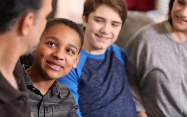 Two teenage boys sit with their foster parents